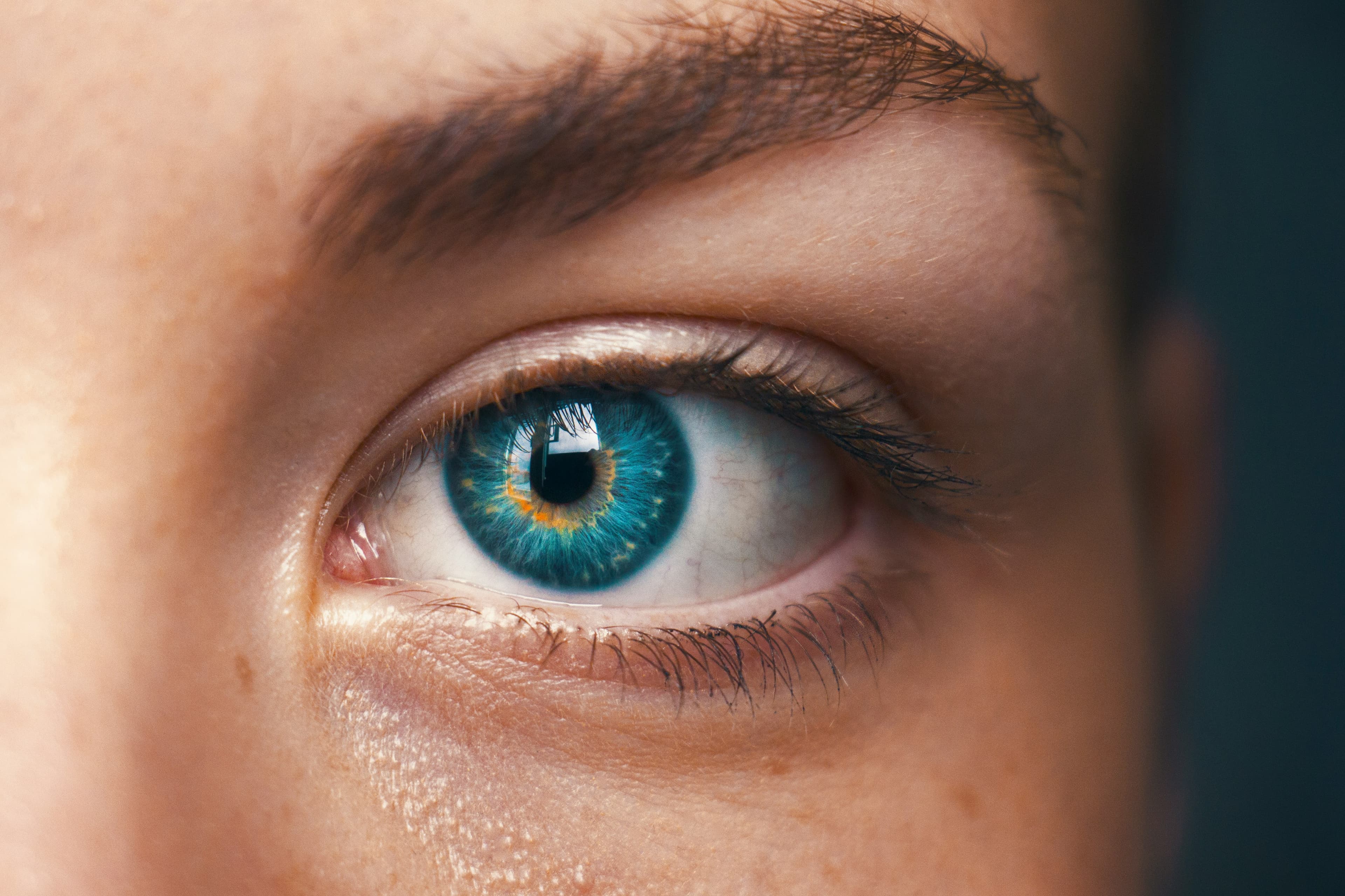 Close-up of a blue-green eye, the eyelashes and iris sharp in daylight